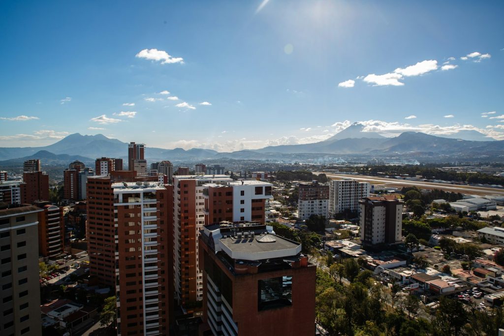Vista de la Ciudad de Guatemala con edificios y volcanes al fondo